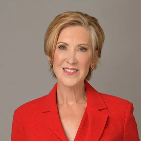 Portrait of a woman in a red suit jacket with a neutral gray background.